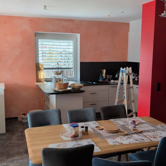 Küche mit Wänden in Terrakotta und einer kräftig roten Akzentfläche neben hellen Fronten.